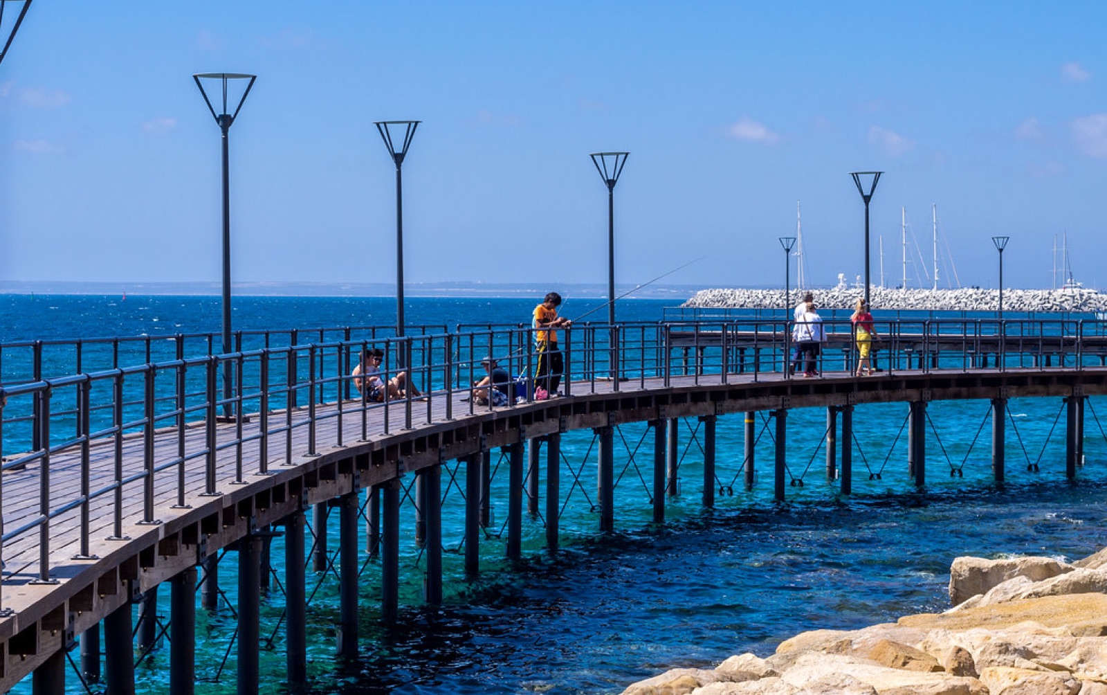 The wooden pier at Limassol's Molos seafront with the marina behind it on a clear summer day