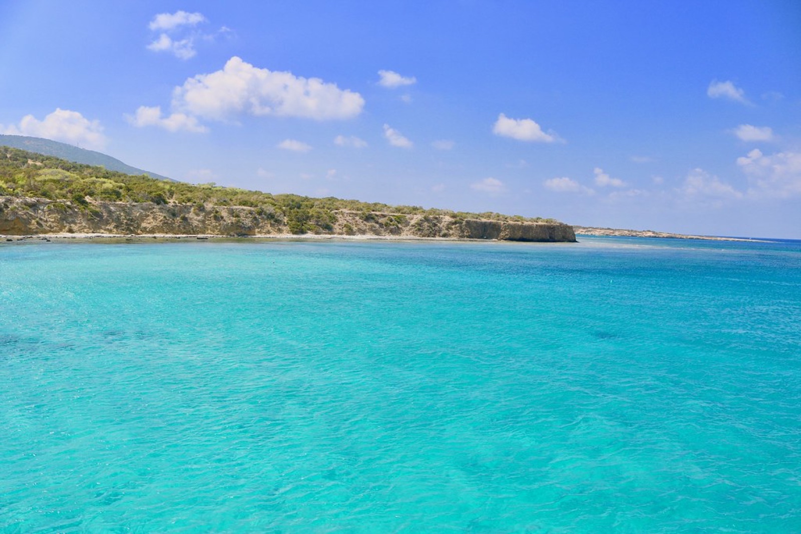 Clear turquoise sea along a rocky Cyprus coastline under a blue sky